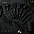 Coukre 14-piece pure black silicone kitchen utensil set fanned out on dark slate, moody product photography